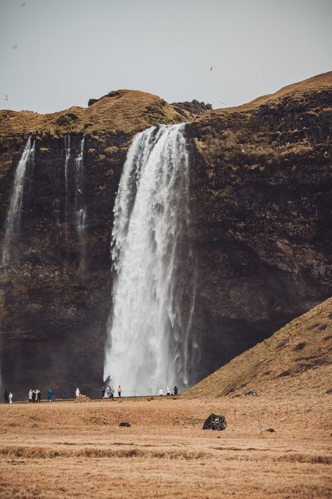 Großer Wasserfall Seljalandsfoss mit Menschen am Fuß des Falls zur Größenorientierung