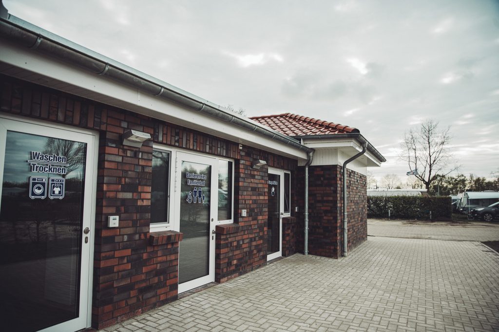 Außenansicht eines Sanitärgebäudes mit Hinweisen zu Waschen und Trocknen am Campingplatz Großes Meer