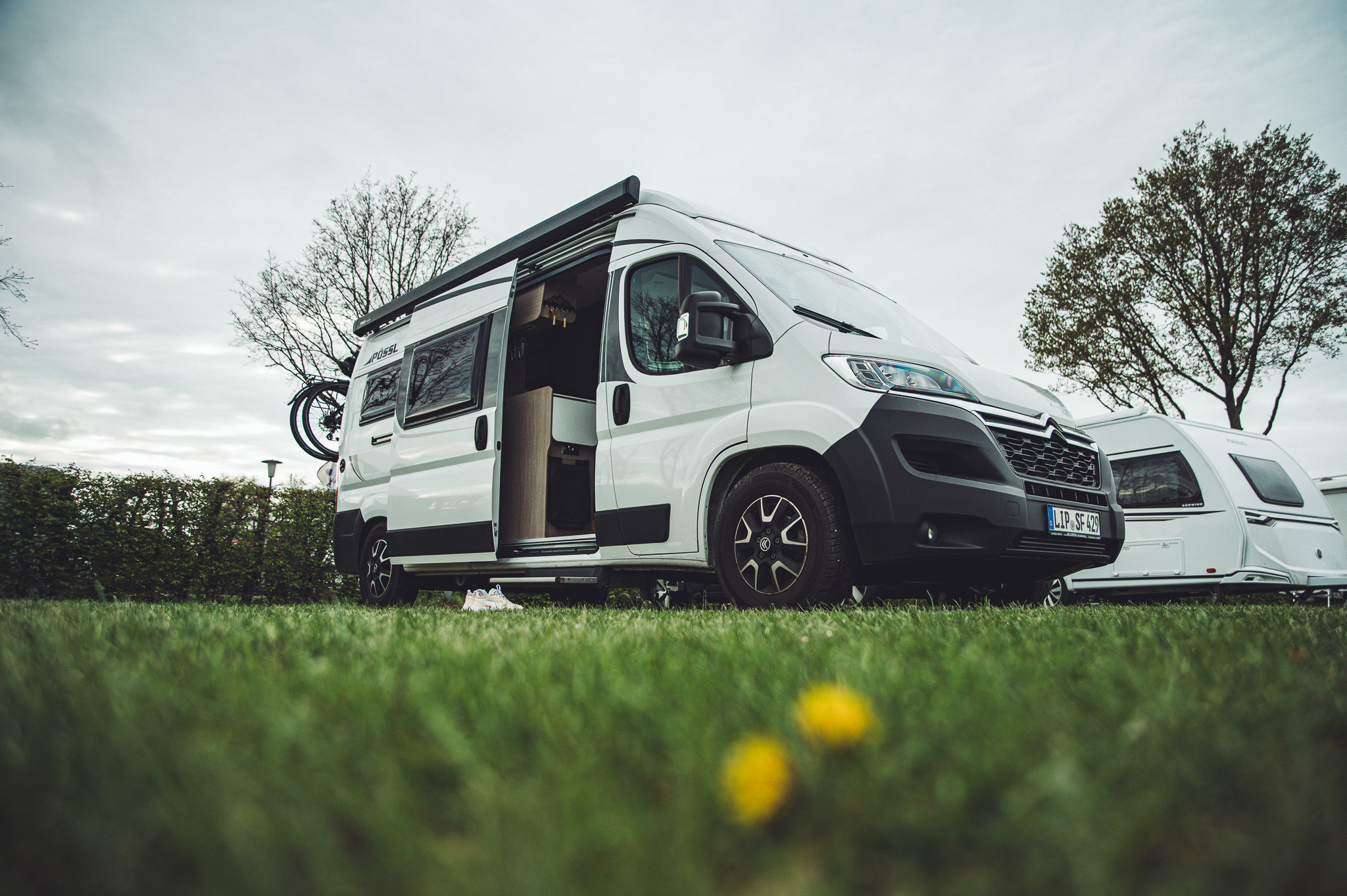 Weißer Campervan mit offener Schiebetür auf einer Wiese am Campingplatz Großes Meer