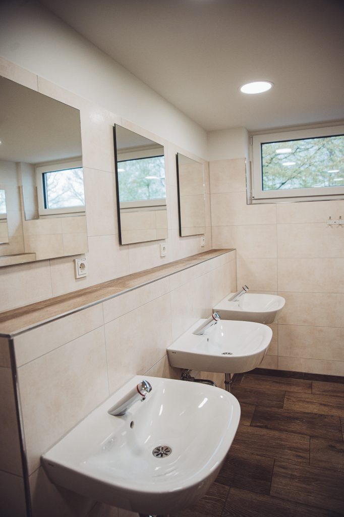 Mehrere Waschbecken mit Spiegeln und Ablage im Sanitärgebäude am Campingplatz Großes Meer