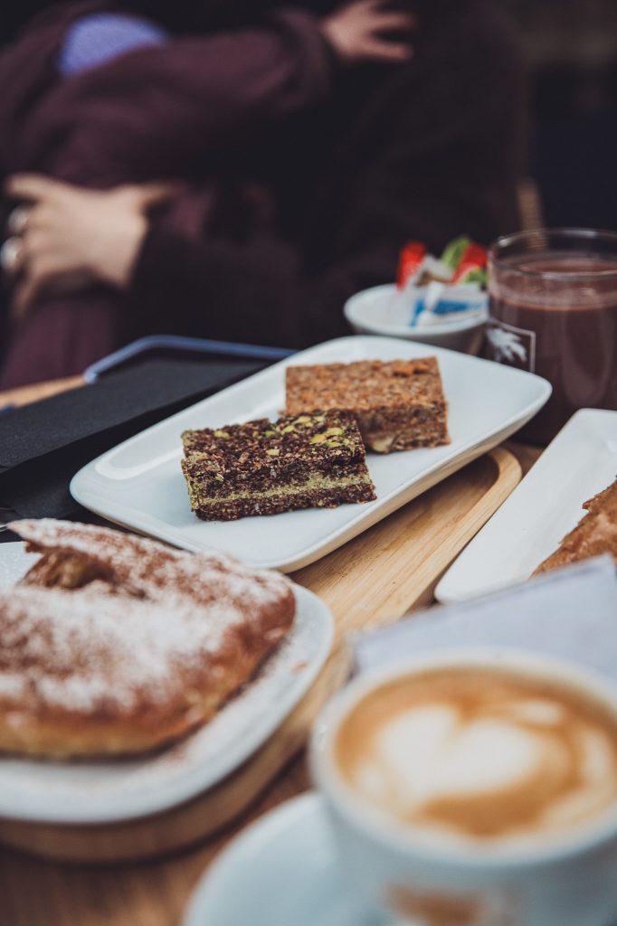 Café-Tisch mit Kuchenstücken, Donut, Cappuccino und heißer Schokolade bei GLYKO in Luxemburg Stadt