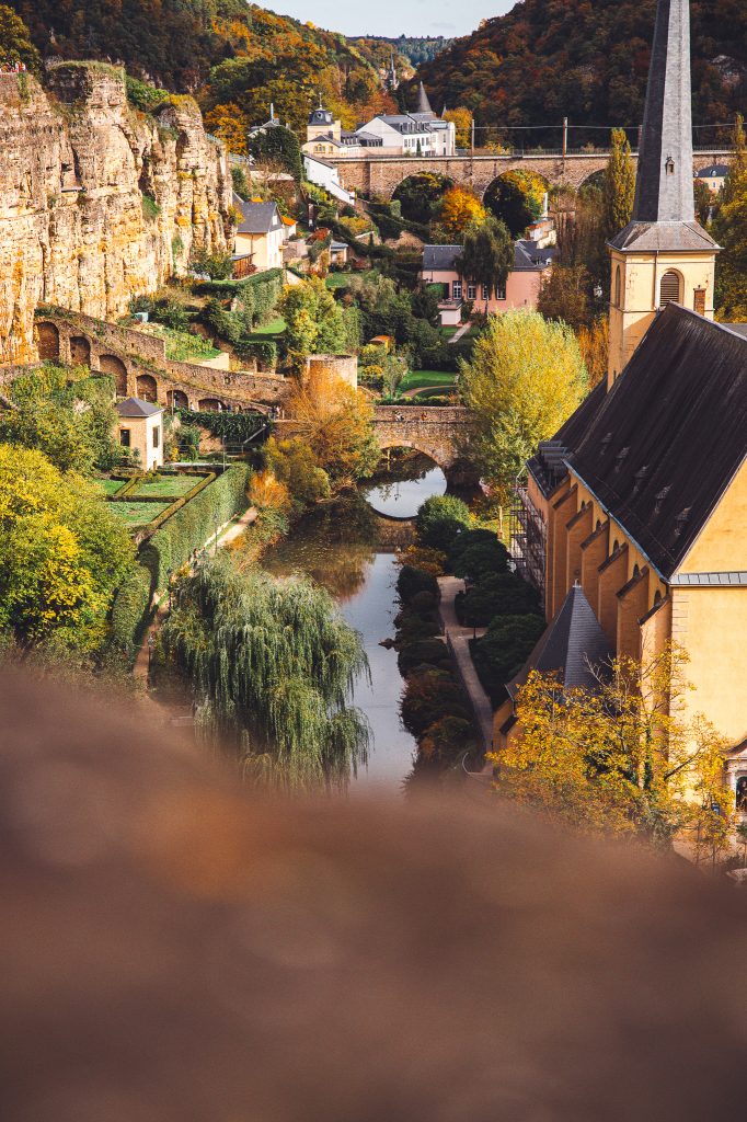 Teleaufnahme vom Grund in Luxemburg Stadt mit Viadukt, Alzette, Felsen und Kirchturm, Herbstfarben