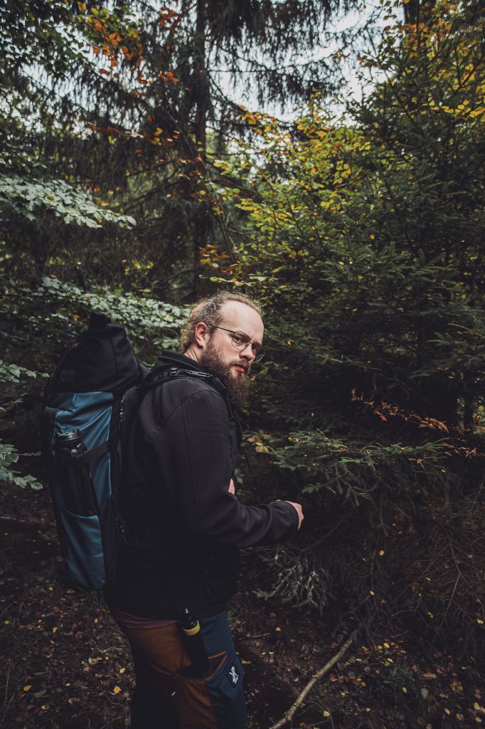 Wanderer mit Rucksack auf schmalem Pfad im Urwald Sababurg