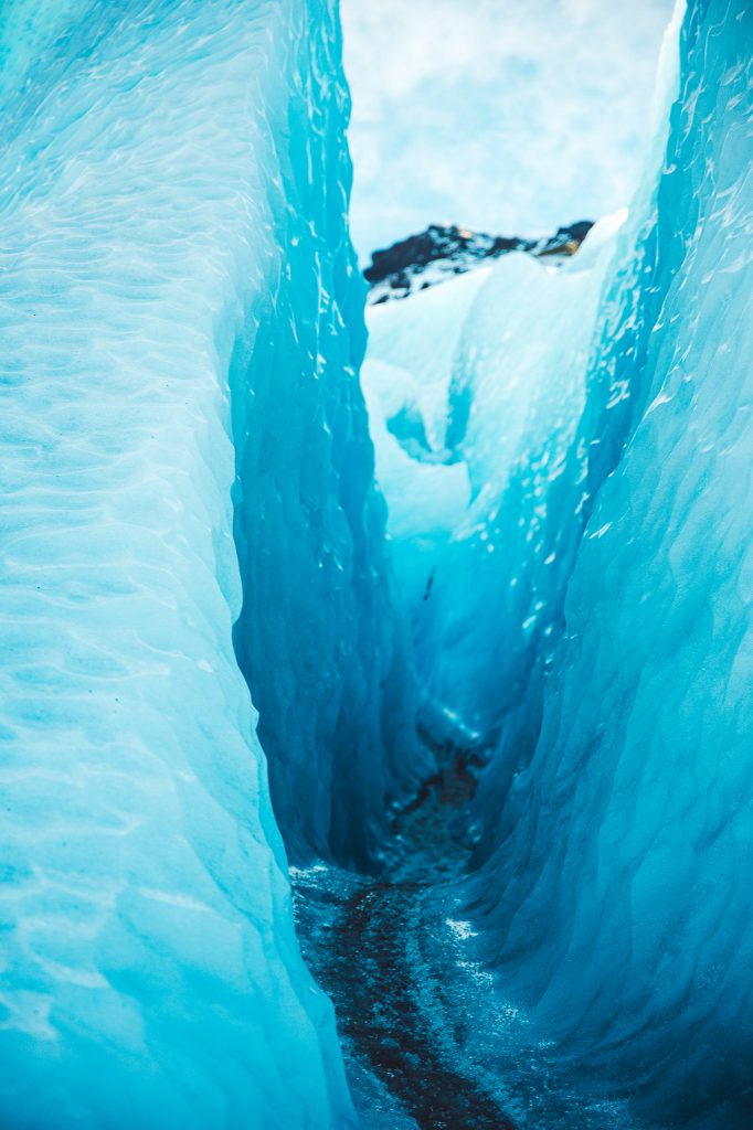 Blick durch eine schmale, tiefblaue Gletscherspalte am Vatnajökull mit welliger Eisstruktur.