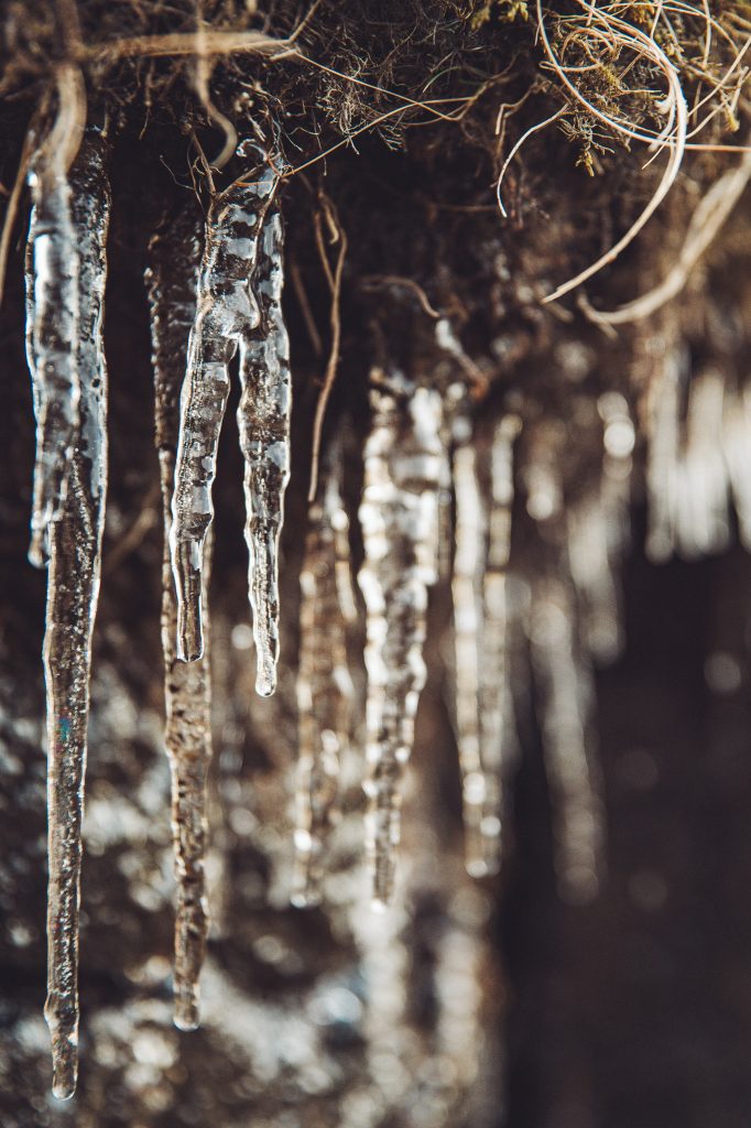 Nahaufnahme von Eiszapfen an einer dunklen Felswand bei Dverghamrar in Island