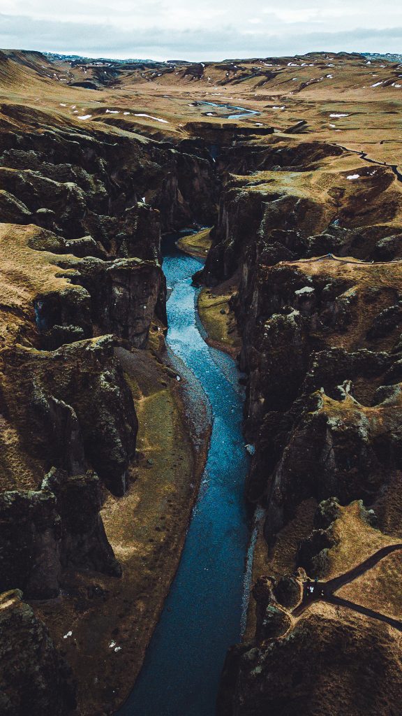 Senkrechte Drohnenaufnahme vom Fjaðrárgljúfur Canyon in Island mit tiefem Flusslauf und steilen dunklen Felswänden