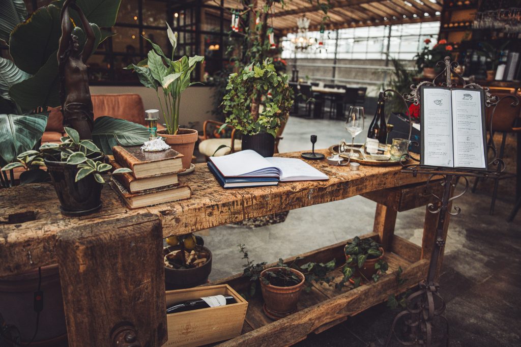 Rustikaler Holztisch mit Pflanzen, Büchern und Speisekarte im Restaurant von Friðheimar