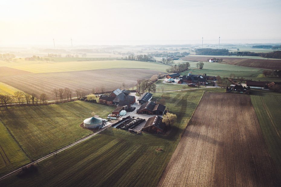 Drohnenaufnahme vom Hof Becker vor der Sandfort mit Hofgebäuden, Feldern und weiter Landschaft rund um den Stellplatz