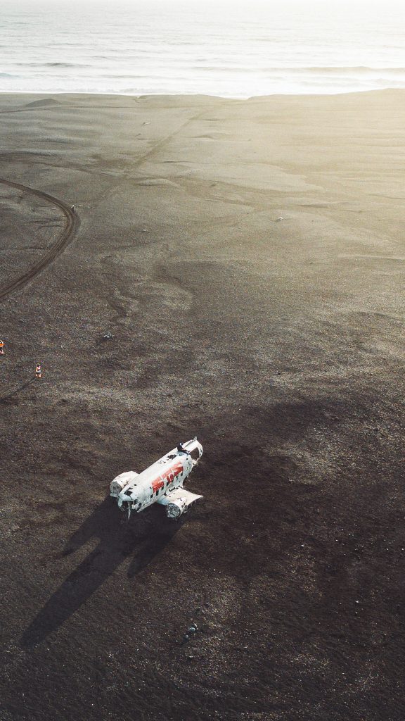 Nahes Luftbild des Flugzeugwracks am Sólheimasandur in Island auf schwarzem Sand mit Meer im Hintergrund