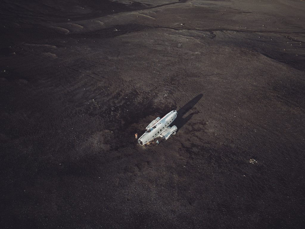 Drohnenaufnahme von oben auf das Flugzeugwrack am Sólheimasandur in Island auf dunklem schwarzem Sand