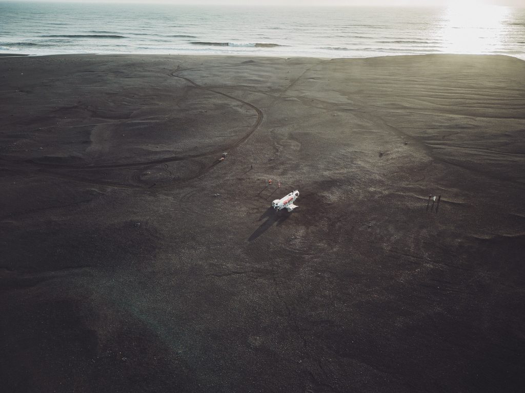 Luftbild vom Sólheimasandur Flugzeugwrack in Island auf schwarzem Sandstrand nahe dem Meer