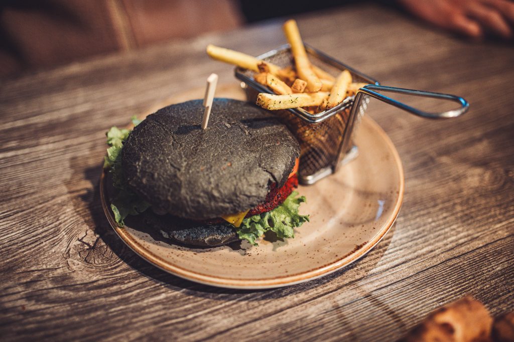 Dunkler Burger mit Pommes auf einem Teller im Systrakaffi Restaurant in Südisland