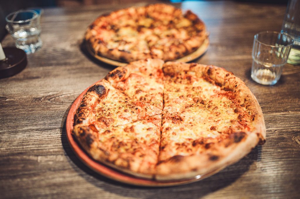 Pizza auf Holztisch im Systrakaffi Restaurant in Südisland als Abendessen nach einem langen Reisetag