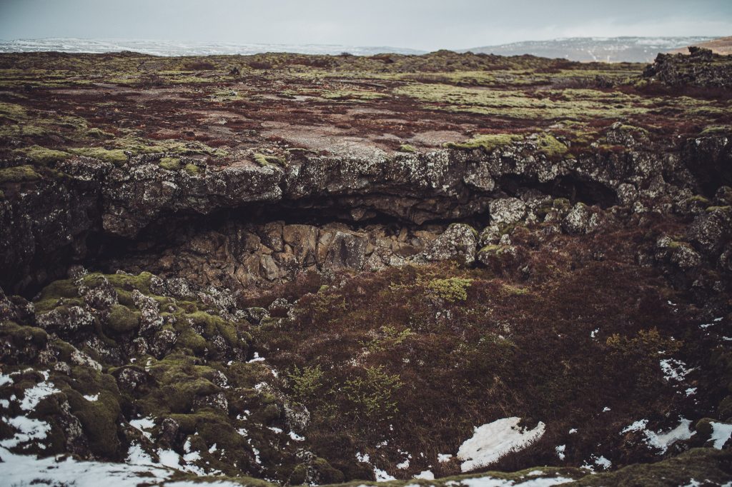 Lavahöhle im felsigen Vulkanfeld bei Eldborg in Island mit Moos und Schneeresten