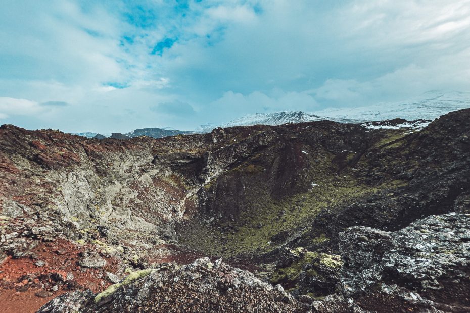 Weiter Blick in den Eldborg-Krater in Island mit felsigen Hängen und Wolkenhimmel