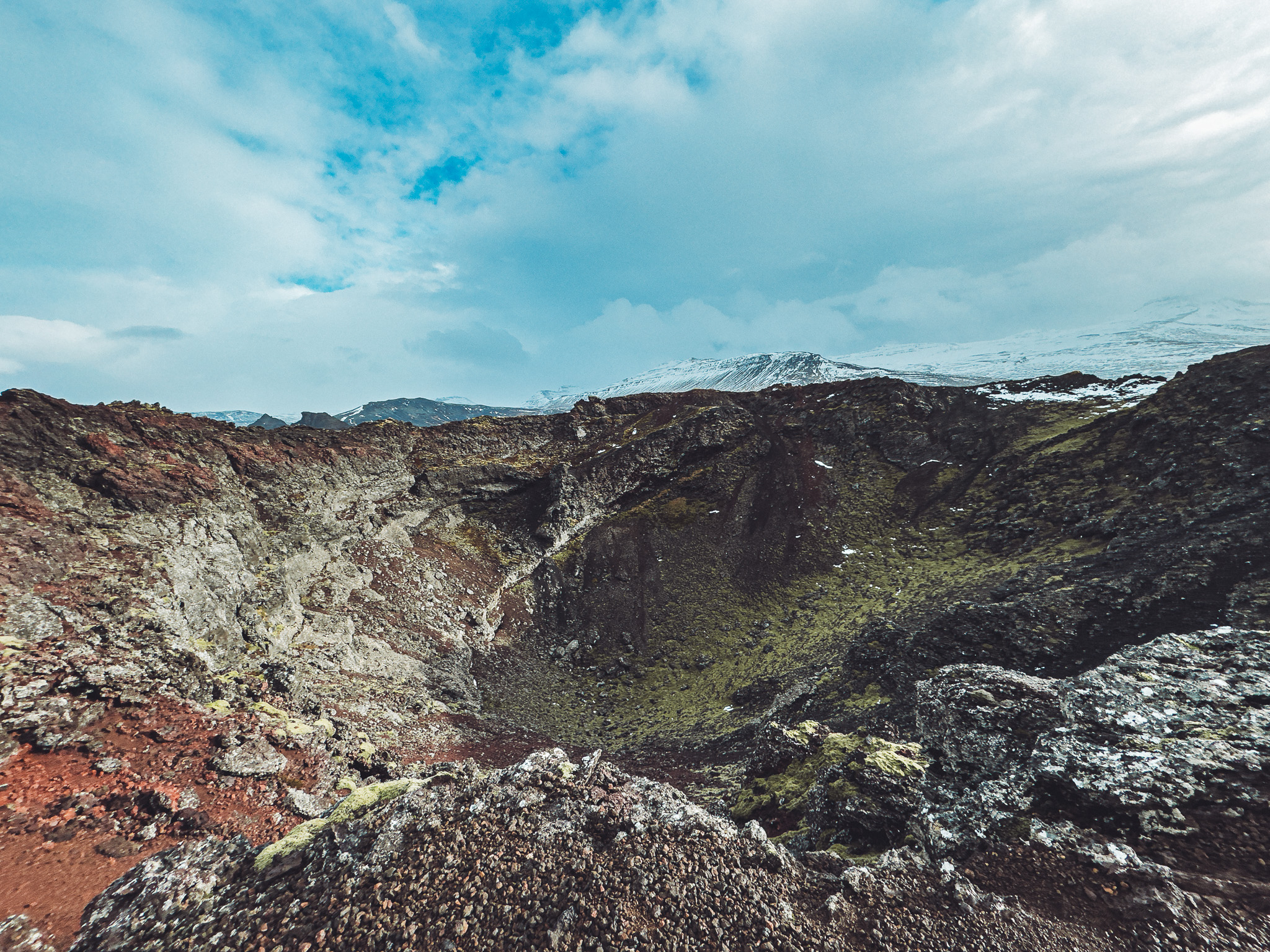 Weiter Blick in den Eldborg-Krater in Island mit felsigen Hängen und Wolkenhimmel