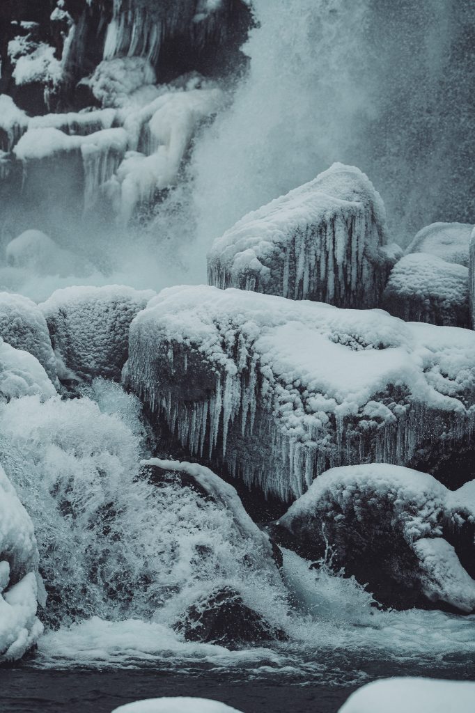 Vereiste Felsen mit Gischt und fließendem Wasser am Öxarárfoss im Þingvellir-Nationalpark