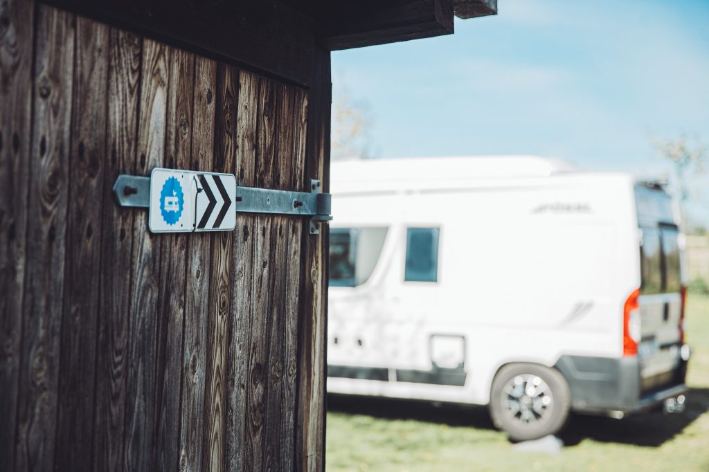 Landvergnügen Wegweiser am Biohof Hümme mit weißem Wohnmobil im Hintergrund