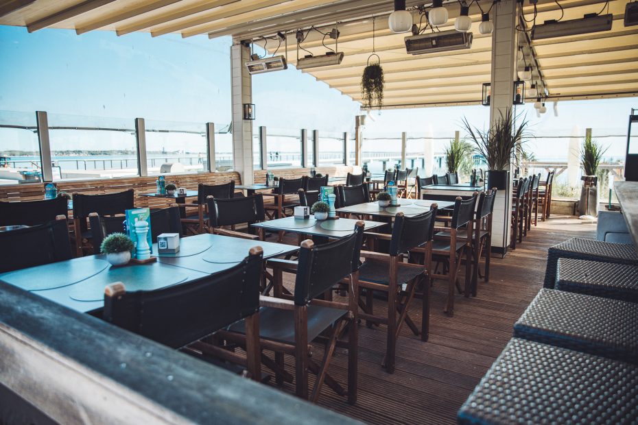 Leere Terrasse des Grande Beach Café in Scharbeutz mit Tischen, Stühlen und Blick auf die Ostsee