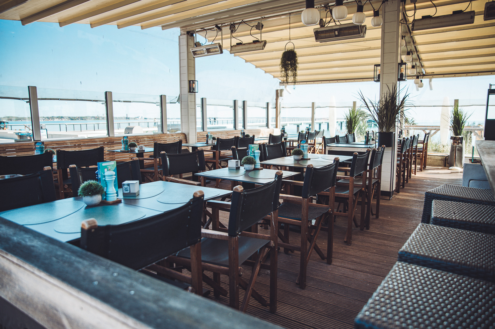 Leere Terrasse des Grande Beach Café in Scharbeutz mit Tischen, Stühlen und Blick auf die Ostsee