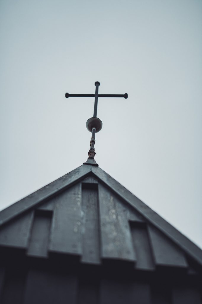 Wir schauen an der Búðakirkja auch auf die kleinen Details. Das Kreuz auf dem schwarzen Holz passt gut zum grauen Winterhimmel.