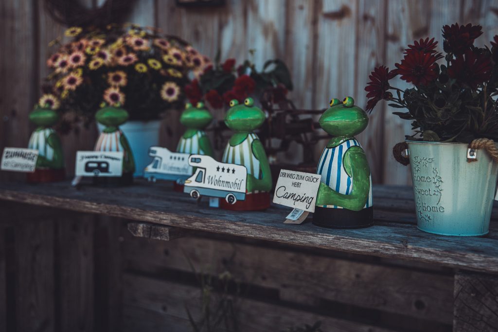 Camping Dekoration mit grünen Figuren, kleinen Wohnmobil Schildern und Blumen im Hofladen von Blümels Hof
