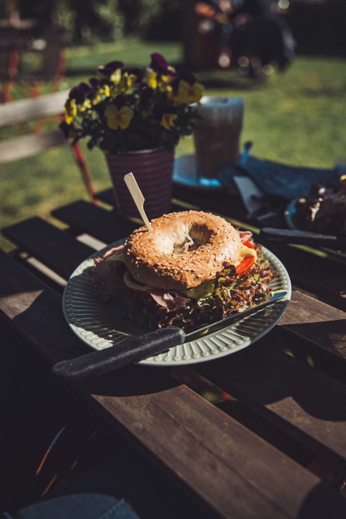 Belegter Bagel mit Salat und Schinken auf einem Teller im Garten vom Hofcafé Blümels