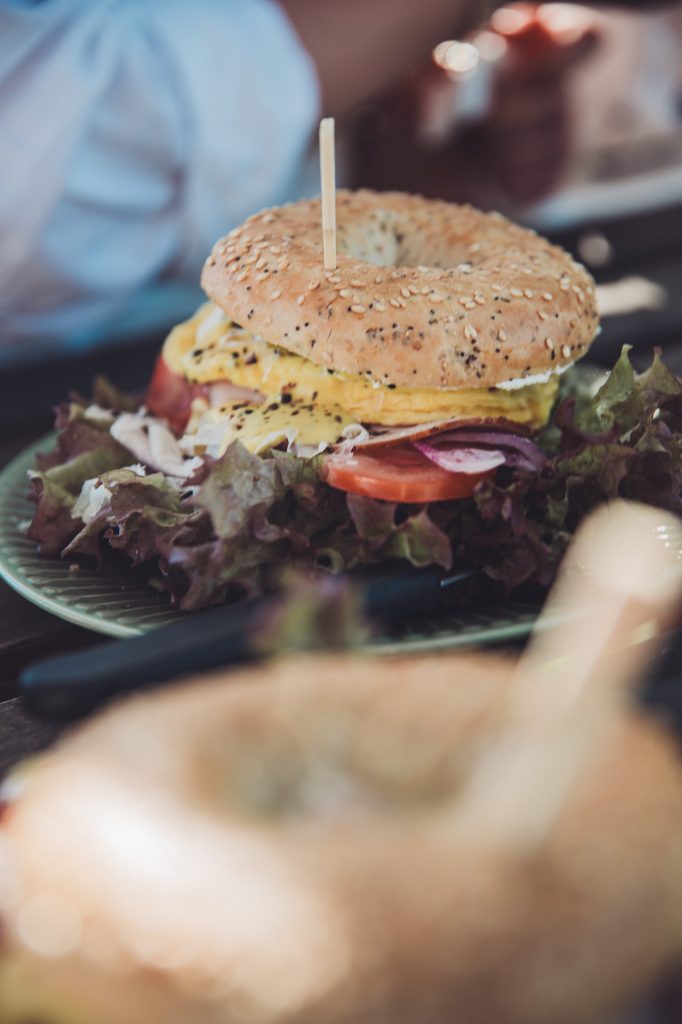 Belegter Bagel auf einem Teller im Garten vom Hofcafé Blümels bei Buxtehude mit unscharfem Vordergrund