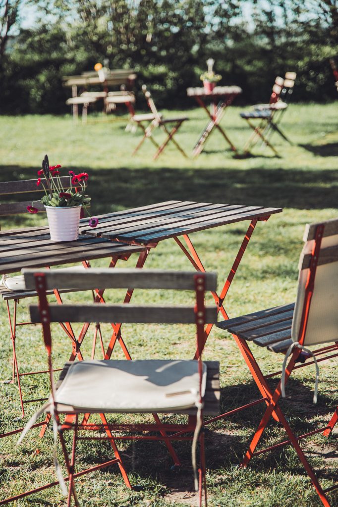 Holztisch mit Stühlen und Blumentopf im Garten vom Hofcafé Blümels bei Buxtehude