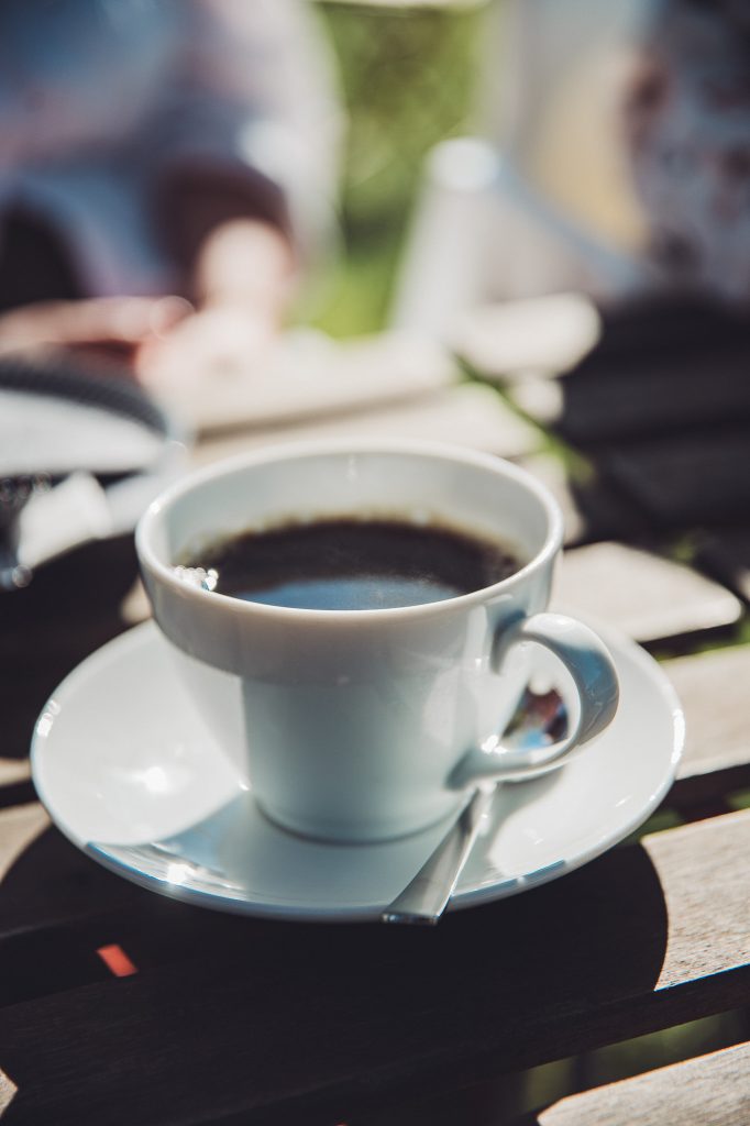 Tasse Kaffee auf einem Holztisch im sonnigen Garten vom Hofcafé Blümels bei Buxtehude
