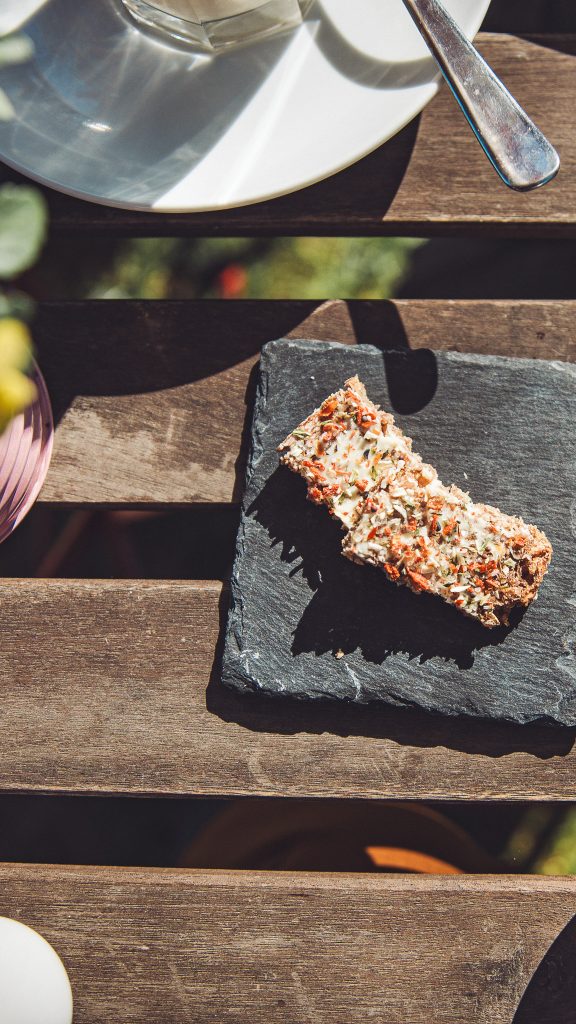 Kleiner Snack auf einer Schieferplatte auf einem Holztisch im Garten vom Hofcafé Blümels