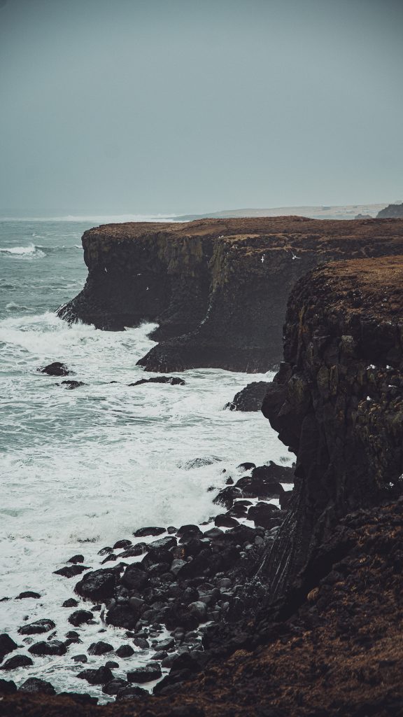 Schwarze Steilküste bei Gatklettur mit Wellen, Gischt und Möwen auf Snæfellsnes