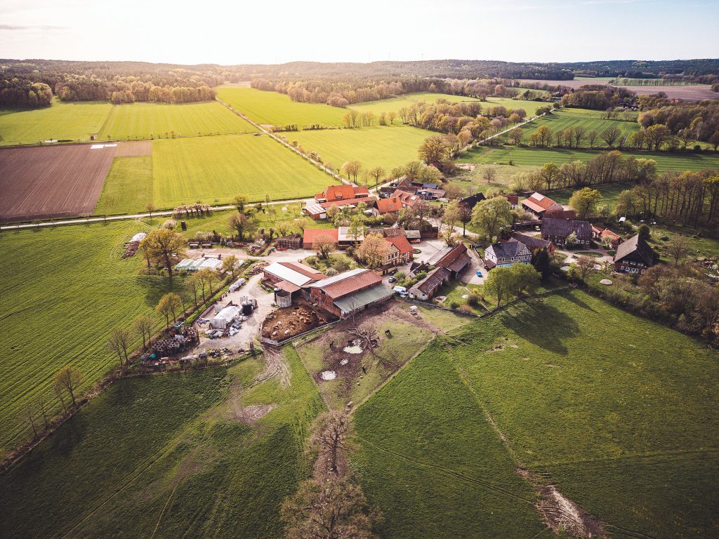 Drohnenaufnahme vom Gerkenhof Merten bei Clenze mit Hofgebäuden, Feldern, Wiesen und Wald im Hintergrund