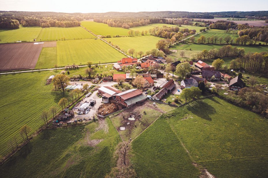 Drohnenaufnahme vom Gerkenhof Merten bei Clenze mit Hofgebäuden, Feldern, Wiesen und Wald im Hintergrund