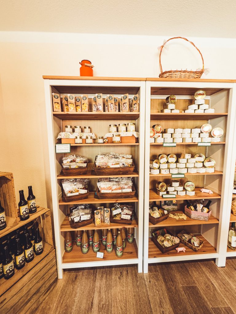 Regale im Hofladen von Krügers Hof mit Gläsern, verpackten Lebensmitteln, Getränken und regionalen Produkten.
