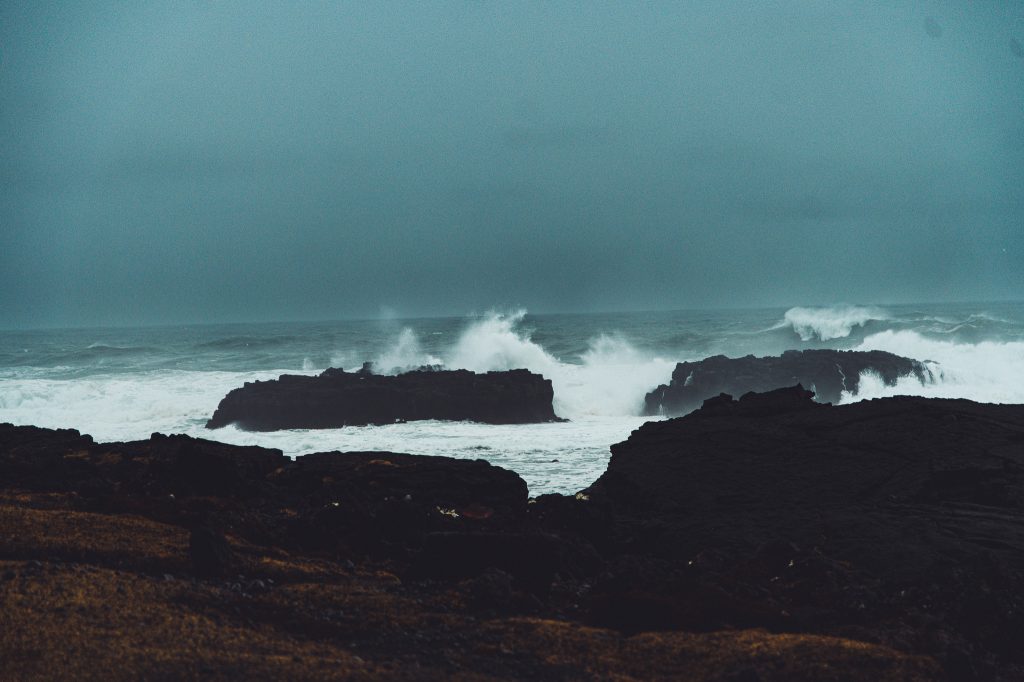 Hohe Wellen brechen an dunklen Lavafelsen nahe dem Leuchtturm von Malarrif auf Snæfellsnes