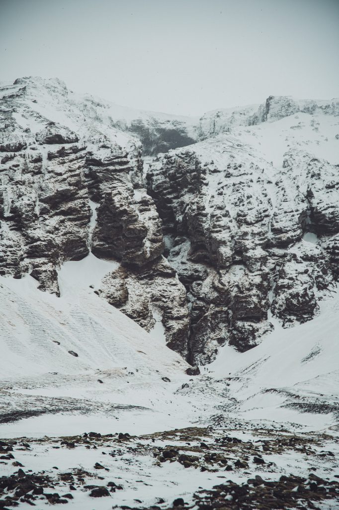 Weite Ansicht der Rauðfeldsgjá Gorge mit Schnee, dunklen Felsen und schmalem Zugang zur Schlucht