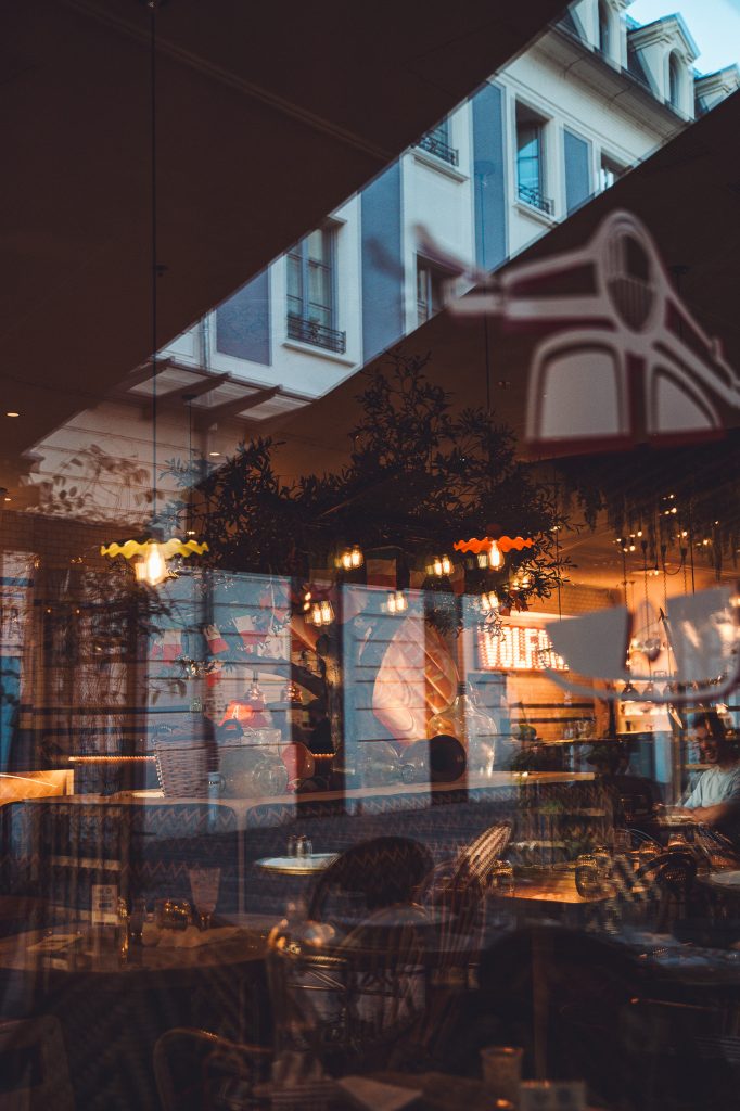Spiegelnde Fensterfront eines warm beleuchteten Restaurants in Lyon