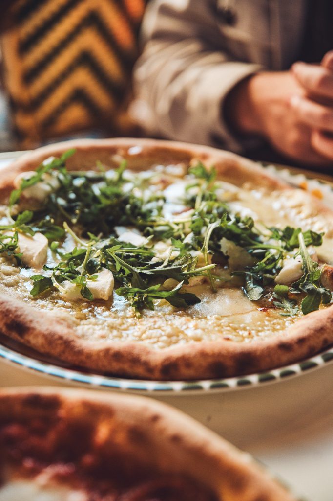 Pizza mit Rucola und Ziegenkäse auf einem gedeckten Restauranttisch in Lyon
