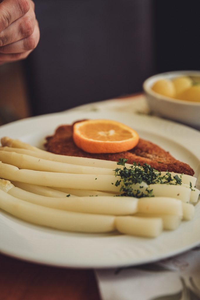 Teller mit weißem Spargel, Schnitzel, Kartoffeln und Orange in der Spargelwirtschaft Heuer