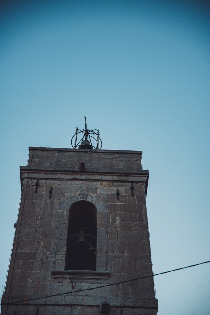 Historischer steinerner Kirchturm mit Glocke vor blauem Himmel in Toulon