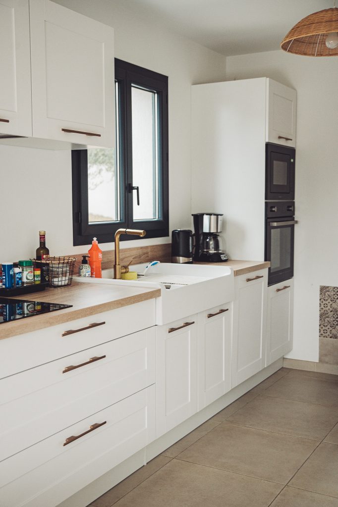 Weiße Küche mit Holzarbeitsplatte, Spülbecken, Kaffeemaschine und Backofen in einer Ferienwohnung bei Toulon