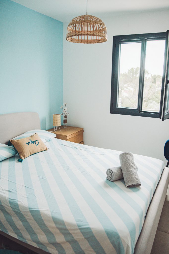 Helles Schlafzimmer mit Doppelbett, Handtüchern und geöffnetem Fenster in einer Ferienwohnung bei Toulon