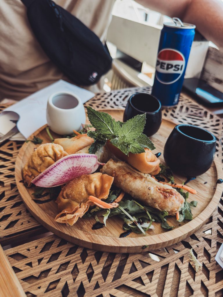 Platte mit Frühlingsrollen, Teigtaschen, Salat und Minze in einem Strandrestaurant in Toulon