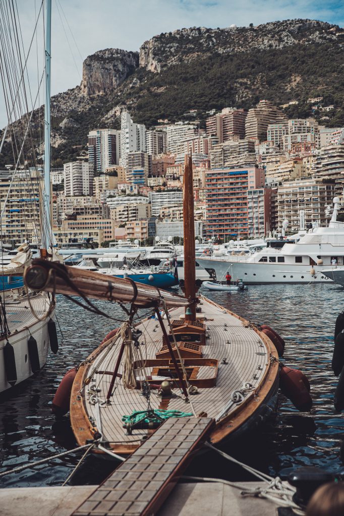 Holzsegelboot und Yachten im Port Hercule vor der dicht bebauten Skyline von Monaco